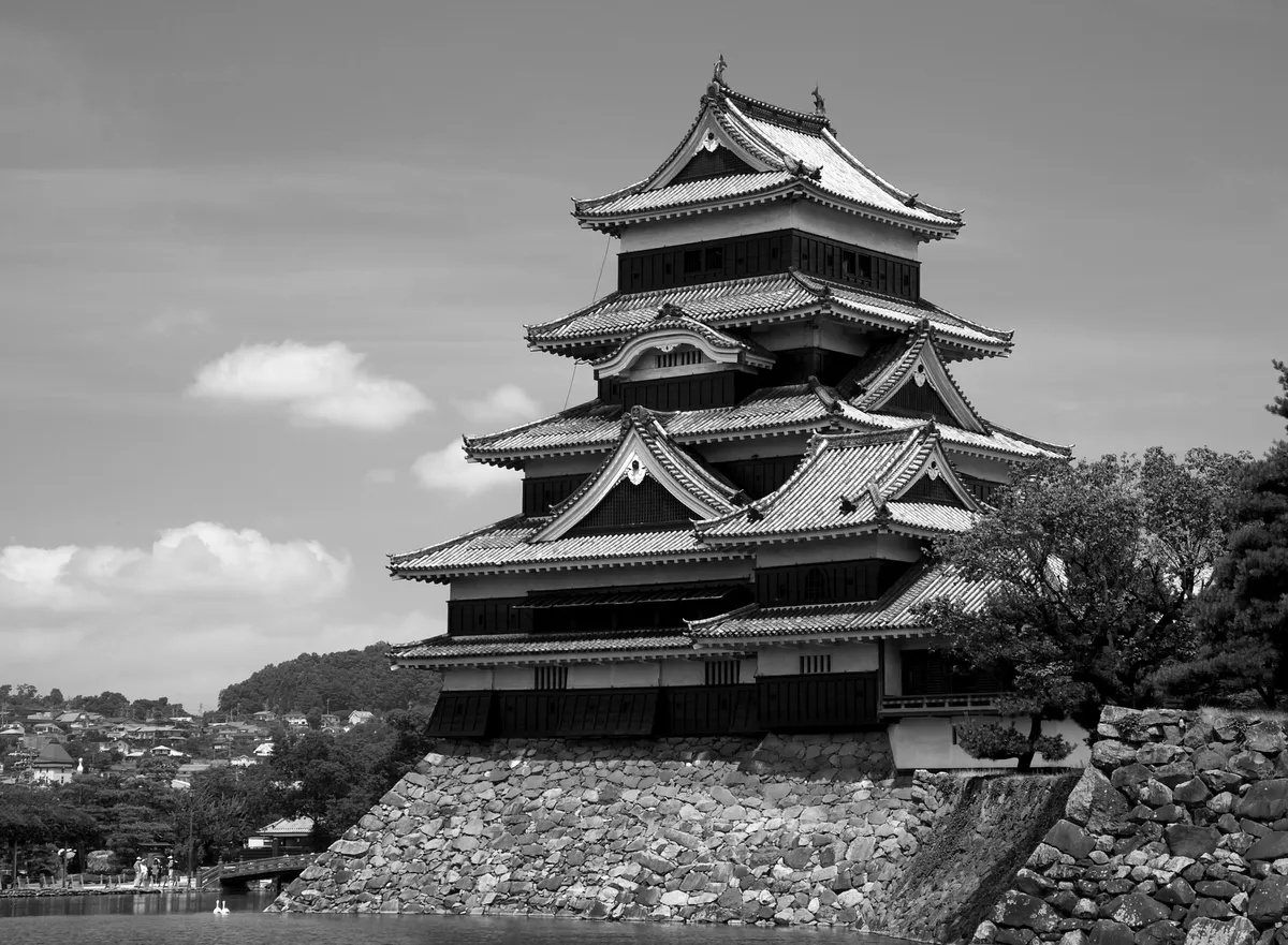 Thành Matsumoto tường gỗ đen tuyền soi bóng xuống hào nước với dãy núi Anpơ Nhật Bản phủ tuyết phía sau